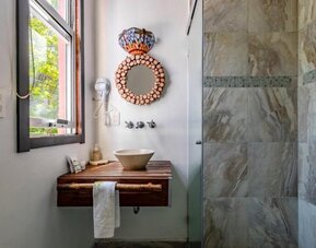 Guest bathroom featuring a vessel sink, wooden vanity, decorative mirror, natural light, and a tiled walk-in shower at Casa Anzures Suites.
