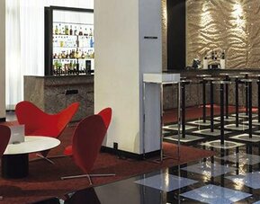 Contemporary bar and lounge featuring vibrant red seating, high-top bar stools, and a well-stocked bar at Hilton Madrid Aeropuerto.