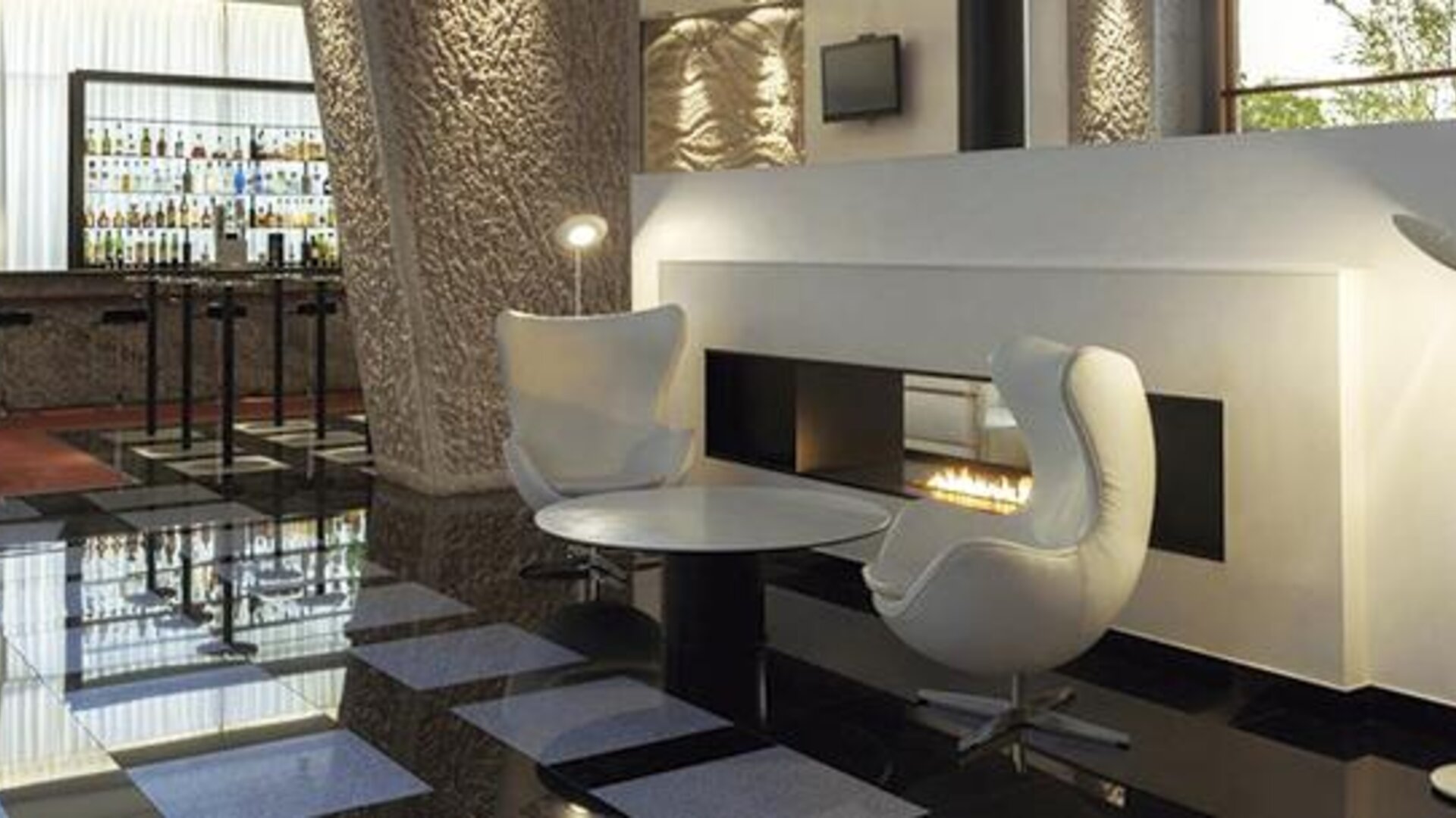 Stylish lounge area featuring contemporary white seating, a modern fireplace, and easy access to the hotel bar at Hilton Madrid Aeropuerto.