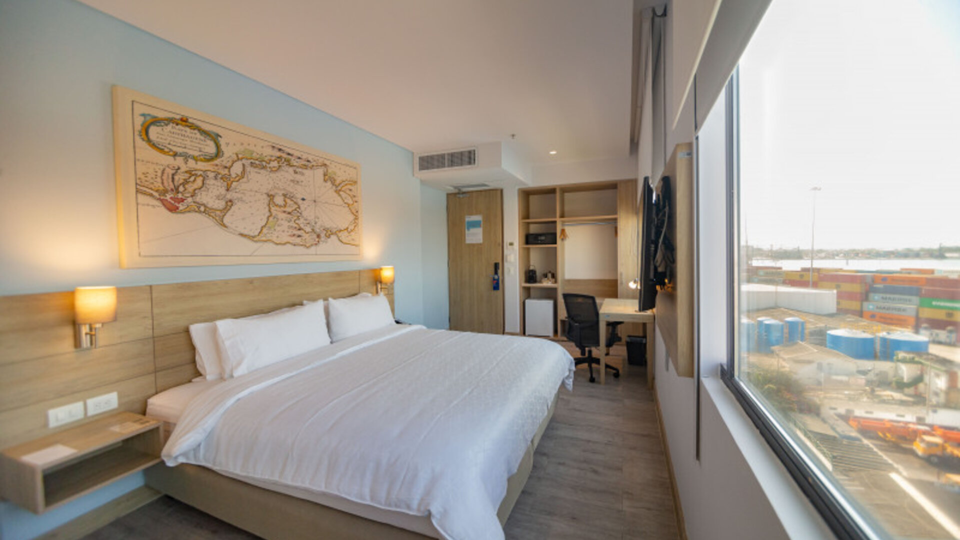 Spacious king guest room featuring abundant natural light, a dedicated workspace, and large windows overlooking the port at Holiday Inn Express Cartagena Manga.
