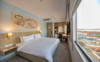 Spacious king guest room featuring abundant natural light, a dedicated workspace, and large windows overlooking the port at Holiday Inn Express Cartagena Manga.
