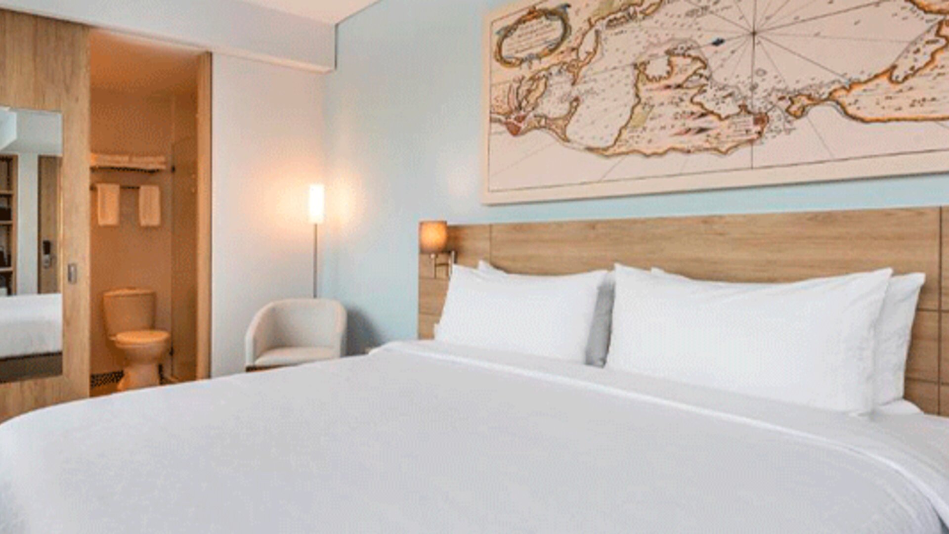 Comfortable king guest room featuring a large bed, contemporary furnishings, and map-inspired wall artwork at Holiday Inn Express Cartagena Manga.