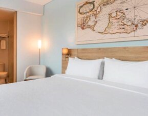 Comfortable king guest room featuring a large bed, contemporary furnishings, and map-inspired wall artwork at Holiday Inn Express Cartagena Manga.