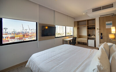 Bright guest room featuring a large bed, television, workspace, storage area, and views of the port at Holiday Inn Express Cartagena Manga.