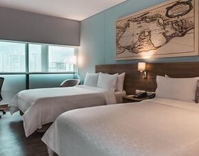 Modern guest room featuring two beds, a dedicated workspace, television, and large windows at Holiday Inn Express Cartagena Manga.