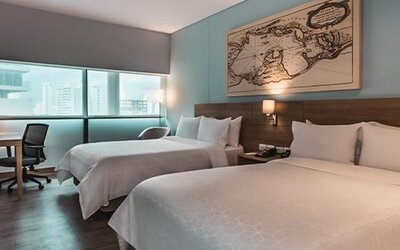 Modern guest room featuring two beds, a dedicated workspace, television, and large windows at Holiday Inn Express Cartagena Manga.