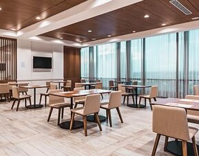 Bright dining area featuring contemporary seating, wood accents, and floor-to-ceiling windows at Holiday Inn Express Cartagena Manga.