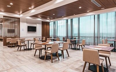 Bright dining area featuring contemporary seating, wood accents, and floor-to-ceiling windows at Holiday Inn Express Cartagena Manga.