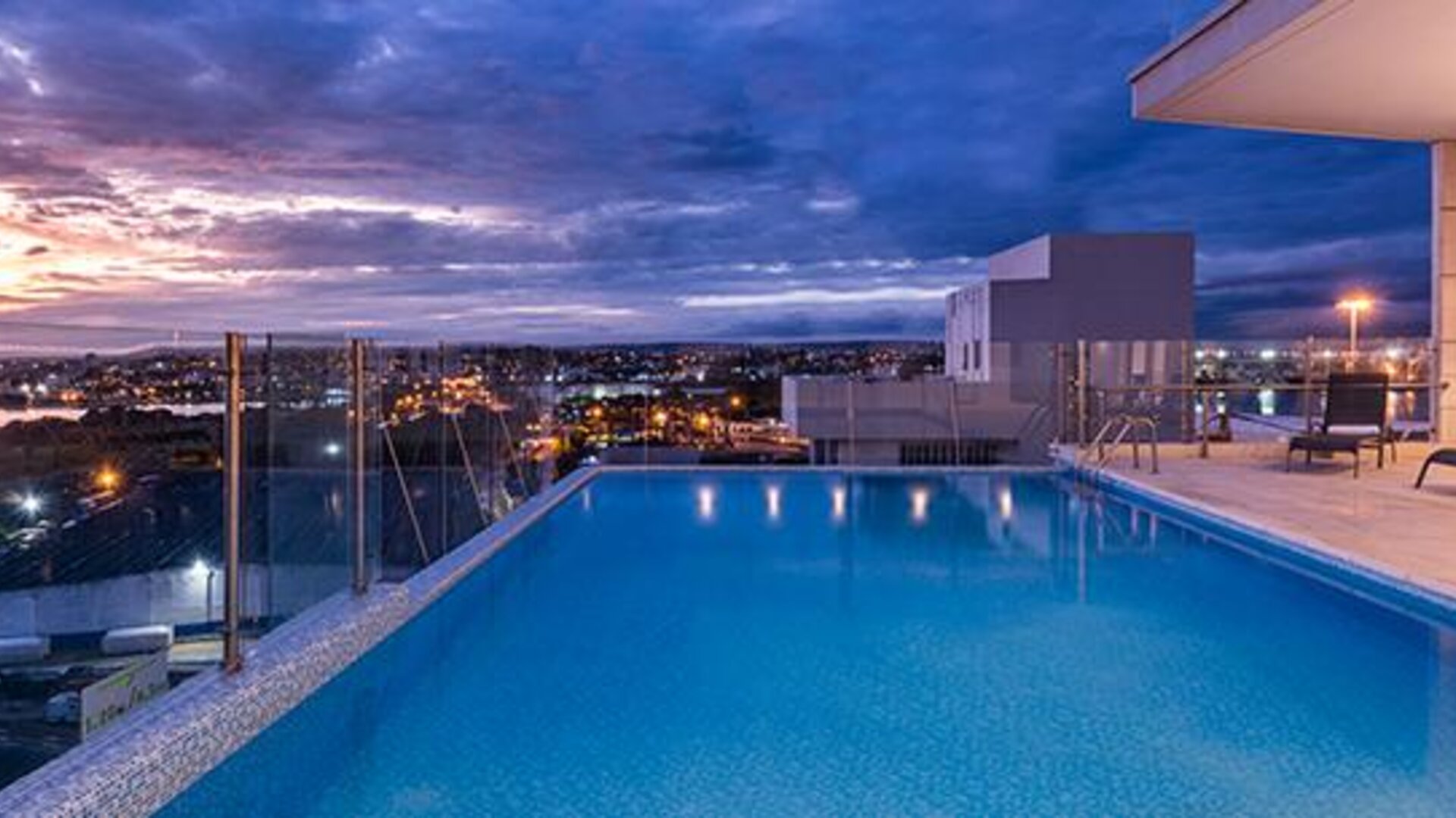 Rooftop outdoor swimming pool featuring panoramic city views and poolside loungers at sunset at Holiday Inn Express Cartagena Manga.