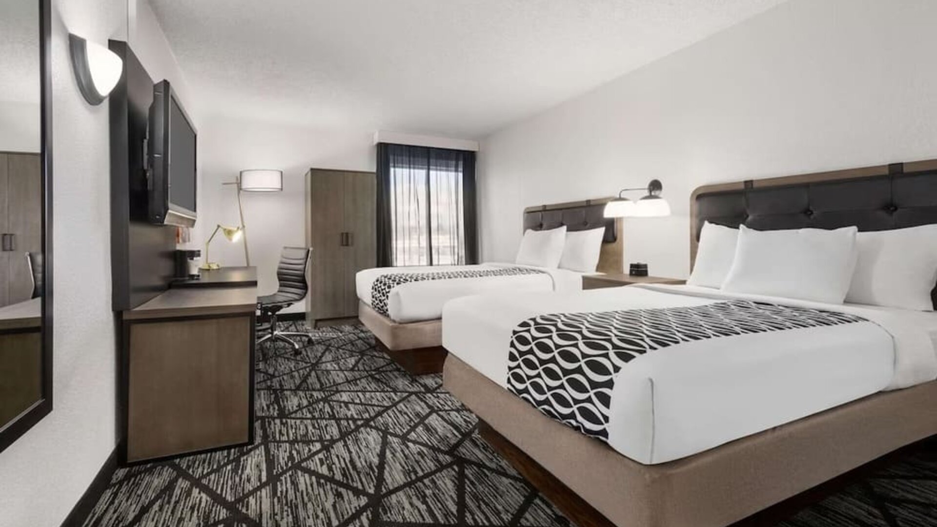 Comfortable guest room featuring two beds, a work desk, television, wardrobe, and modern furnishings at La Quinta Inn & Suites By Wyndham Cleveland Airport West.