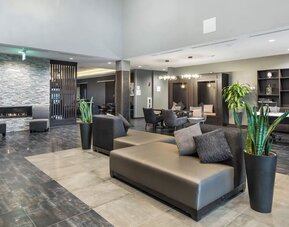 Stylish lobby seating area featuring contemporary sofas, a fireplace, plants, and additional lounge seating at Holiday Inn & Suites Silicon Valley - Milpitas.