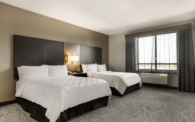 Spacious guest room featuring two beds, bedside lighting, a large window, and comfortable contemporary furnishings at Holiday Inn & Suites Silicon Valley - Milpitas.