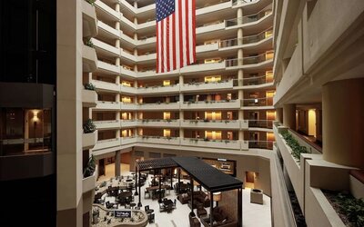 Impressive multi-storey atrium featuring open balconies, lounge seating, dining areas, and a large American flag at Embassy Suites by Hilton Crystal City National Airport.