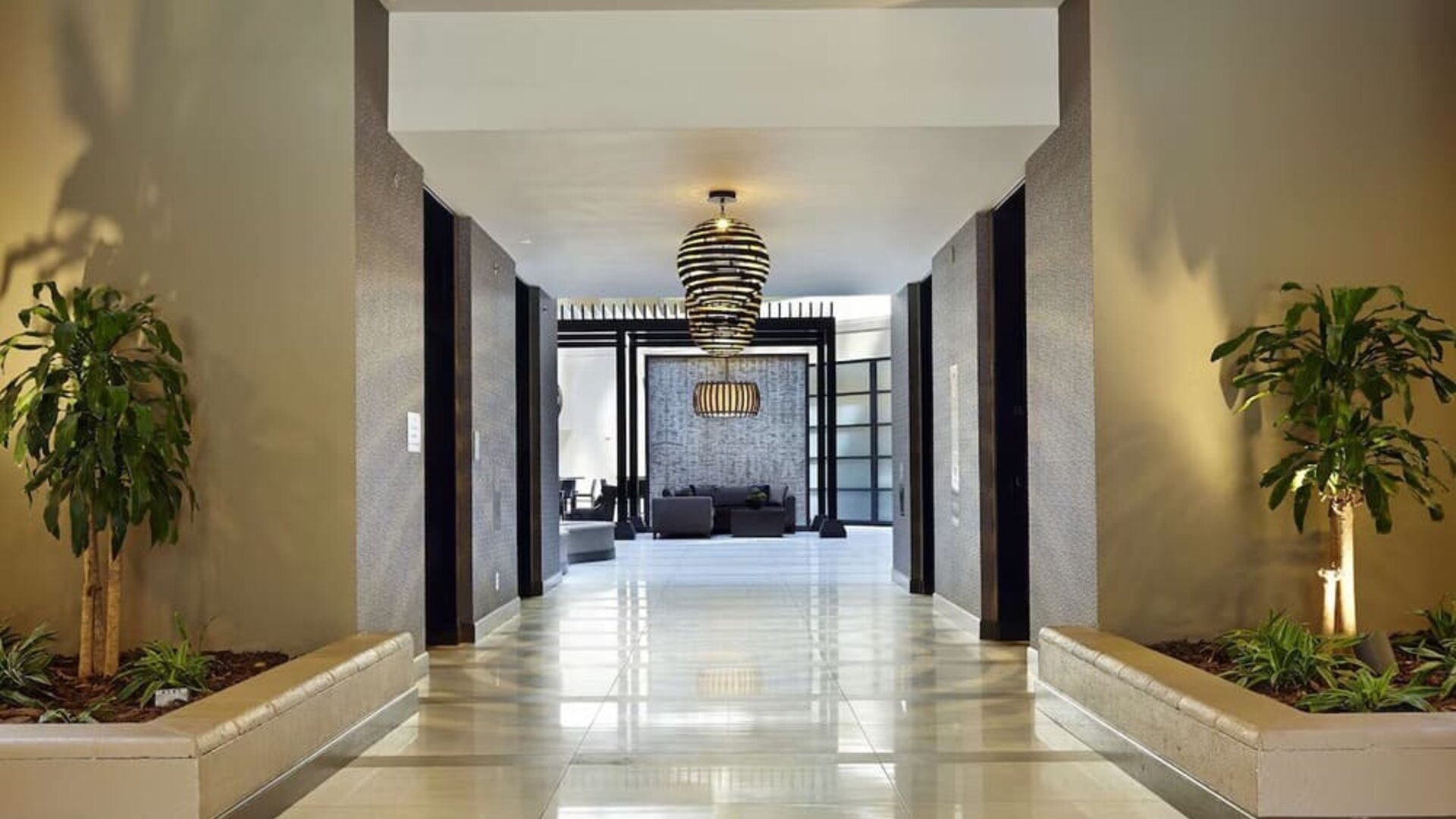 Contemporary hotel corridor and lobby area featuring decorative lighting, indoor greenery, and modern design at Embassy Suites by Hilton Crystal City National Airport.