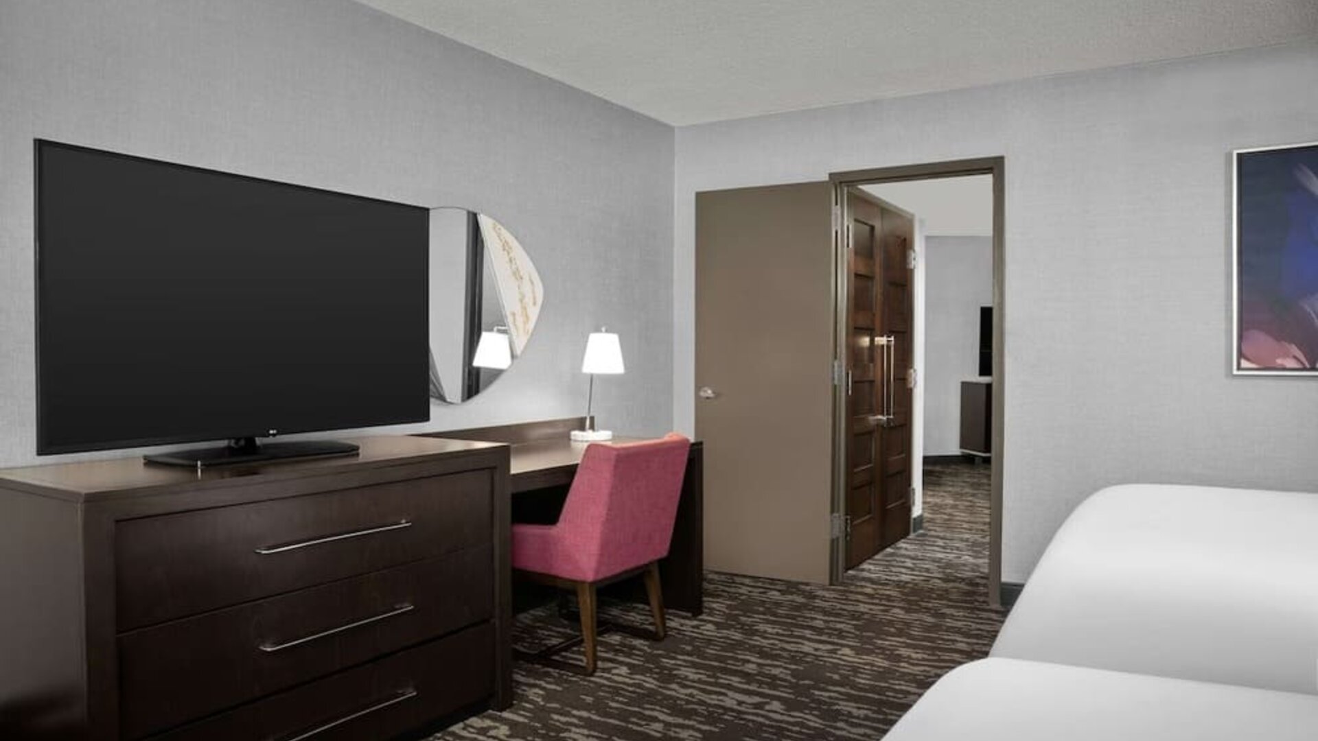 Comfortable guest room featuring two beds, a large television, desk and chair, and contemporary furnishings at Embassy Suites by Hilton Crystal City National Airport.