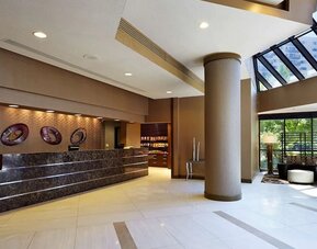 Modern reception area featuring a spacious front desk, contemporary décor, seating, and abundant natural light at Embassy Suites by Hilton Crystal City National Airport.