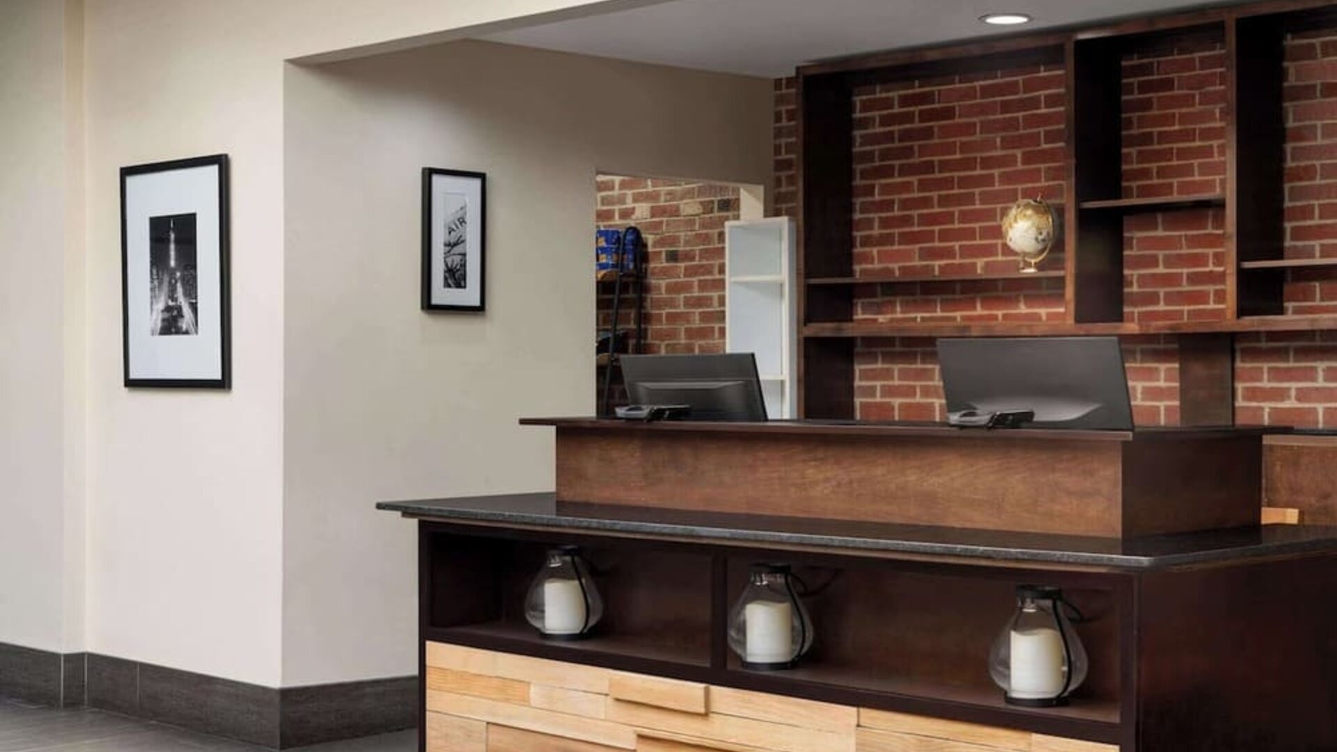 Contemporary reception desk featuring warm wood finishes, exposed brick accents, and modern décor at Wyndham Garden Pittsburgh Airport.