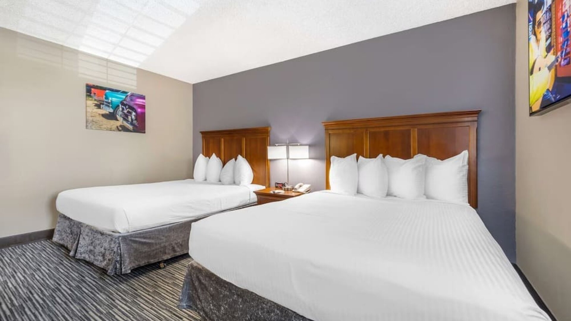 Guest room featuring two beds with wooden headboards, bedside lighting, and colourful wall art. Best Western McCarran Inn.