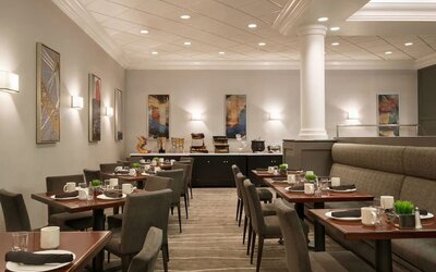 Dining area featuring set tables, upholstered seating, buffet station, and contemporary wall art. Crowne Plaza Englewood.