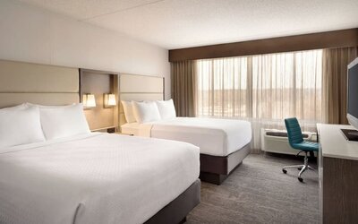 Guest room featuring two beds, large window, workspace, television, and contemporary furnishings. Crowne Plaza Englewood.