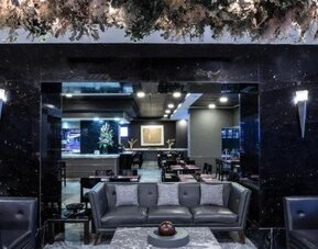 Contemporary hotel dining area with tables, chairs and large street-facing windows. LaiLa Hotel CDMX.