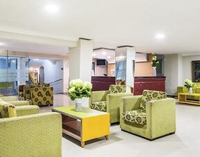 Hotel lobby with green armchairs, sofas, coffee tables and floral arrangements at Hotel Puerta de Oro.