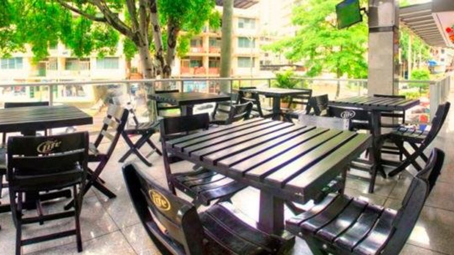 Outdoor terrace with black tables and chairs overlooking trees and surrounding buildings at Hotel Grand International.