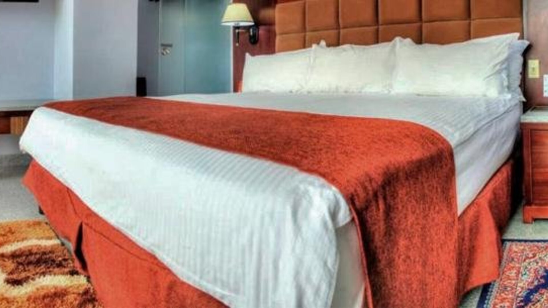 Spacious guest room with a king bed, seating area, desk, television, and large windows at Hotel Grand International.