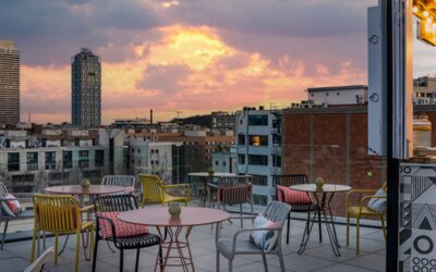 Rooftop terrace with colorful chairs, round tables, lounge seating, and city views at Hotel ibis Styles Barcelona City Bogatell.