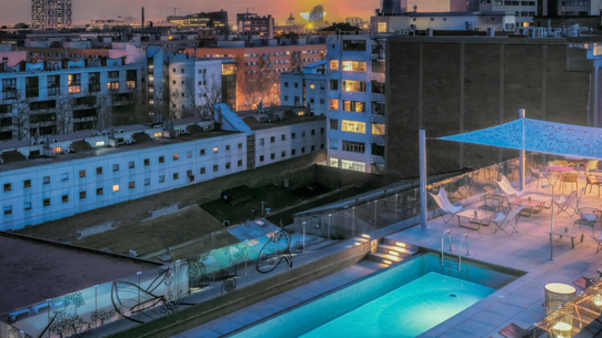 Rooftop pool with lounge chairs, glass railings, canopy, and surrounding city buildings at Hotel ibis Styles Barcelona City Bogatell.