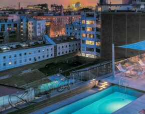 Rooftop pool with lounge chairs, glass railings, canopy, and surrounding city buildings at Hotel ibis Styles Barcelona City Bogatell.