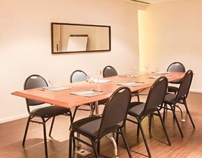 Meeting room with a rectangular table, chairs, notepads, wall mirror, and flip chart at Dazzler by Wyndham Buenos Aires Recoleta.