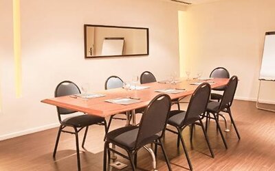 Meeting room with a rectangular table, chairs, notepads, wall mirror, and flip chart at Dazzler by Wyndham Buenos Aires Recoleta.