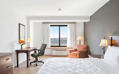 Guest room with a king bed, desk, office chair, armchair, television and large window overlooking the landscape at Holiday Inn Panama Canal.