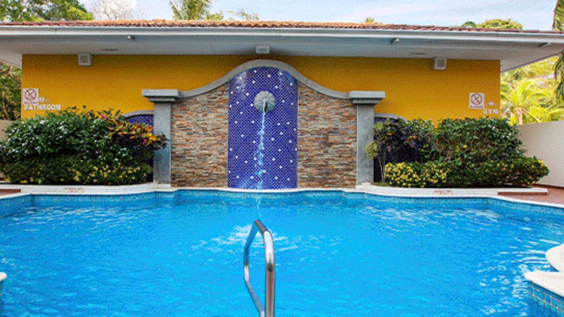 Outdoor swimming pool with blue water, tropical landscaping and a decorative tiled waterfall feature at Holiday Inn Panama Canal.