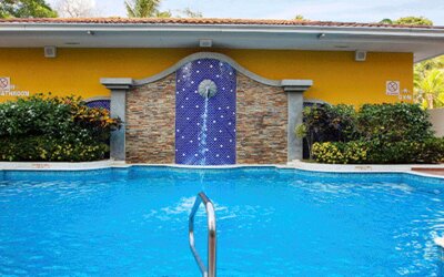 Outdoor swimming pool with blue water, tropical landscaping and a decorative tiled waterfall feature at Holiday Inn Panama Canal.