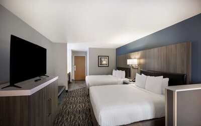 Guest room with two beds, a television, dresser, desk, and seating area at Best Western Plus Mountain View Auburn Inn.