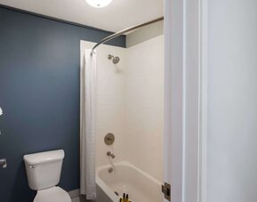 Bathroom with a bathtub, shower, toilet, and dark blue accent wall at Best Western Plus Mountain View Auburn Inn.