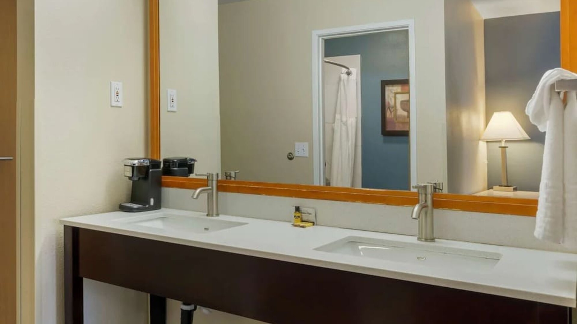 Double-sink vanity with a large mirror, coffee maker, and towels at Best Western Plus Mountain View Auburn Inn.