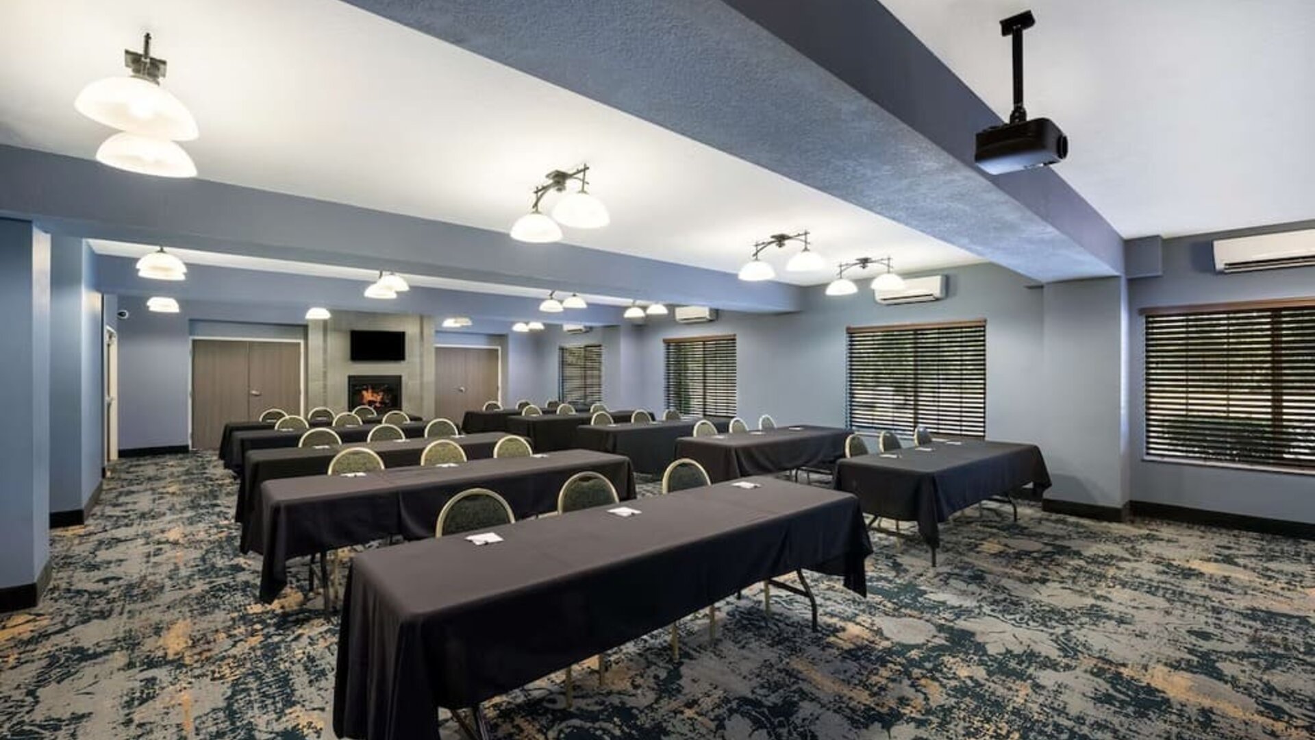 Conference room with rows of tables, chairs, and a presentation screen at Best Western Plus Mountain View Auburn Inn.
