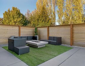 Outdoor patio with wicker seating, artificial turf, and a square fire pit at Best Western Plus Mountain View Auburn Inn.