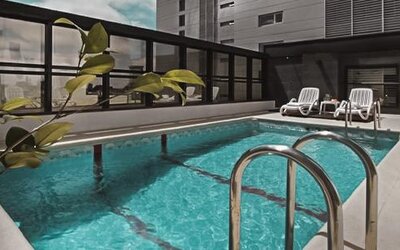 Outdoor swimming pool with turquoise water, metal handrails and white lounge chairs at Ramada by Wyndham Buenos Aires Centro.