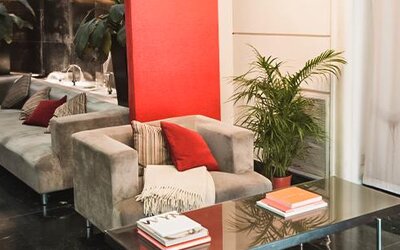 Hotel seating area with gray armchairs and sofas, red cushions, plants and a glass coffee table at Ramada by Wyndham Buenos Aires Centro.