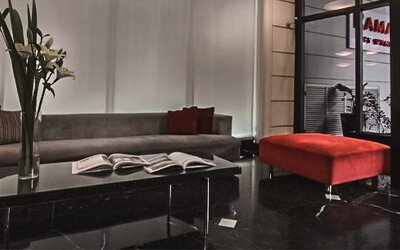 Hotel lounge with a gray sofa, red ottoman, marble coffee table and open books at Ramada by Wyndham Buenos Aires Centro.