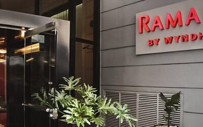 Hotel entrance with glass doors, illuminated Ramada by Wyndham signage and potted plants at Ramada by Wyndham Buenos Aires Centro.