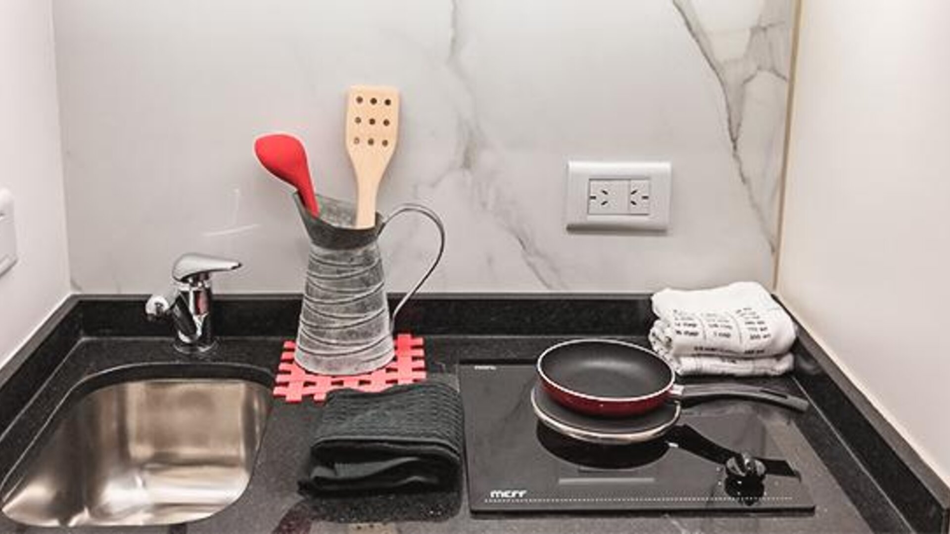 Kitchenette with sink, cookware, utensils and electric stovetop at Ramada by Wyndham Buenos Aires Centro.