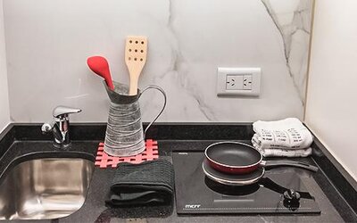 Kitchenette with sink, cookware, utensils and electric stovetop at Ramada by Wyndham Buenos Aires Centro.