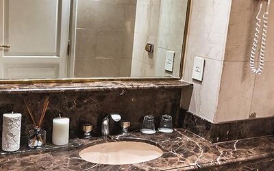 Bathroom vanity with marble countertop, oval sink, large mirror and toiletries at Ramada by Wyndham Buenos Aires Centro.