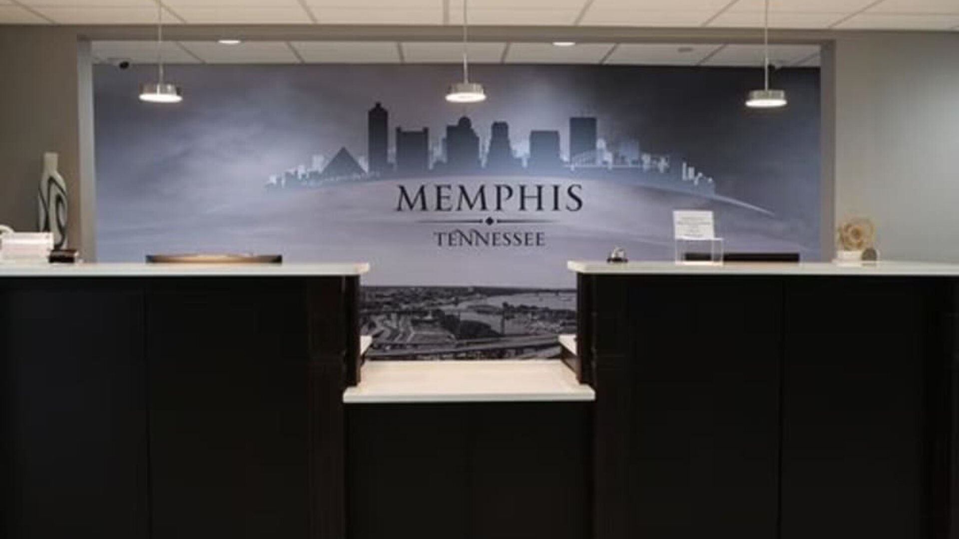 Reception desk at At Home Inn & Suites with a large Memphis, Tennessee cityscape mural behind the front desk.