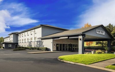 Exterior of Garner by IHG showing the hotel building, covered entrance, landscaped lawn, and parking area.